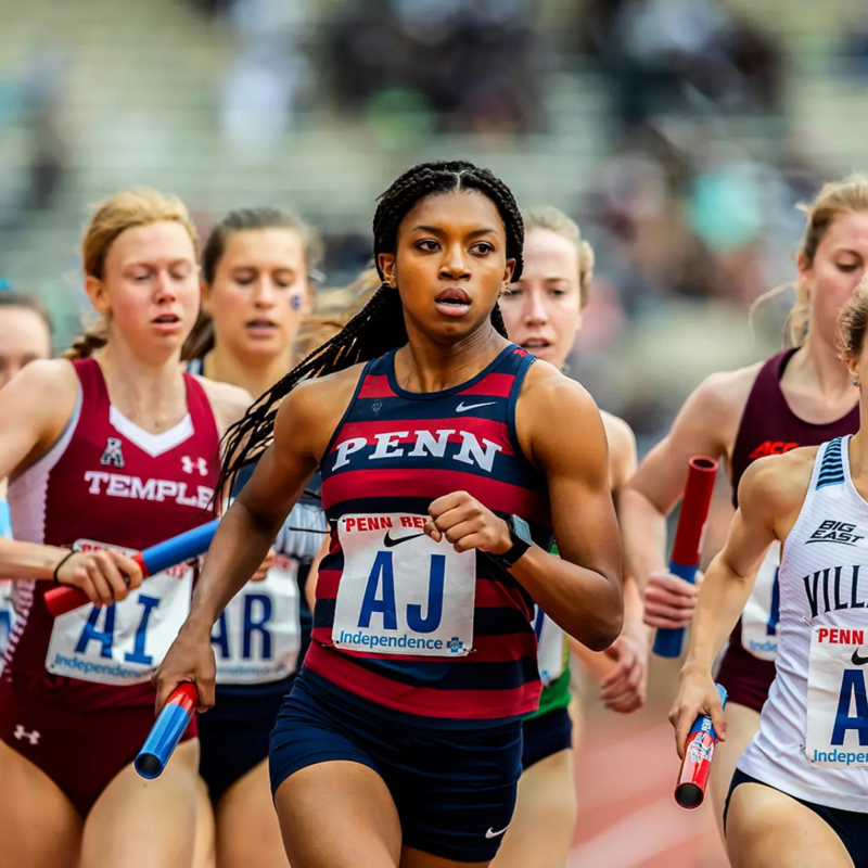 Group of track athletes running led by a person wearing a Penn track uniform