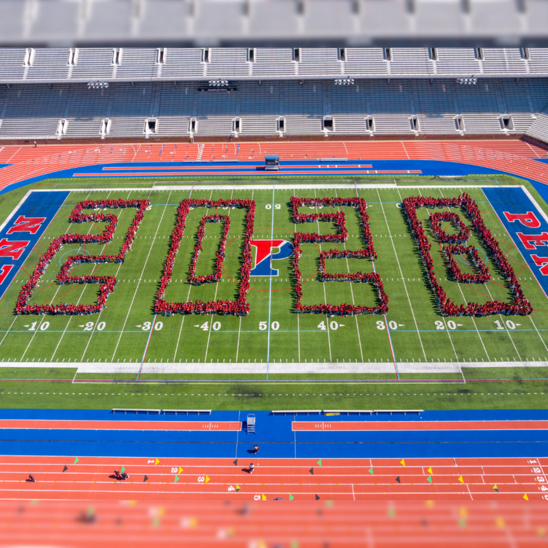 Penn Class of 2028 standing on the football field at Franklin Field organized into the numbers 2028.