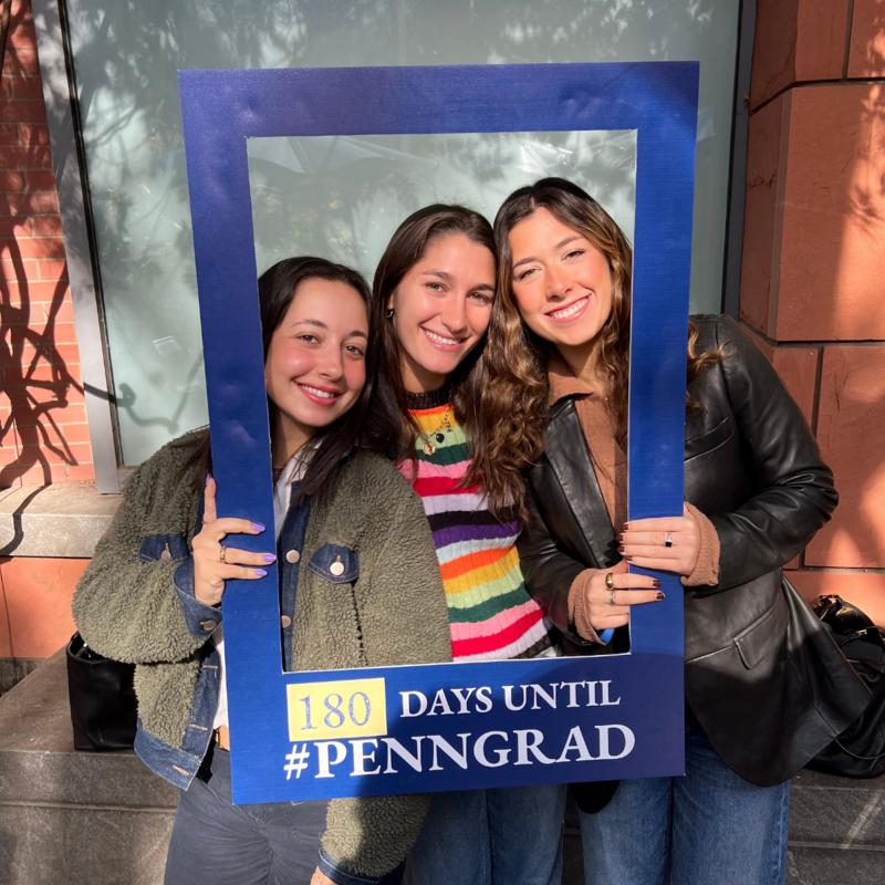 3 students posing for a photo while holding a blue frame that reads "180 Days Until #PennGrad"