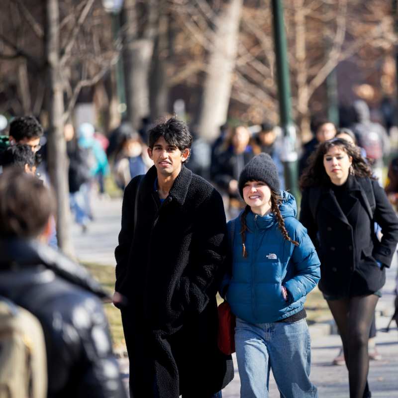 A convoy of students walking to class with book bags, hats and coats on.